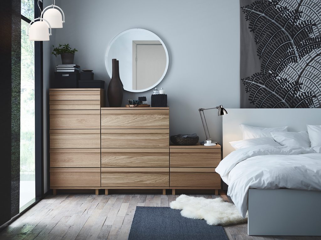 Minimal bedroom with oak drawers and a round mirror