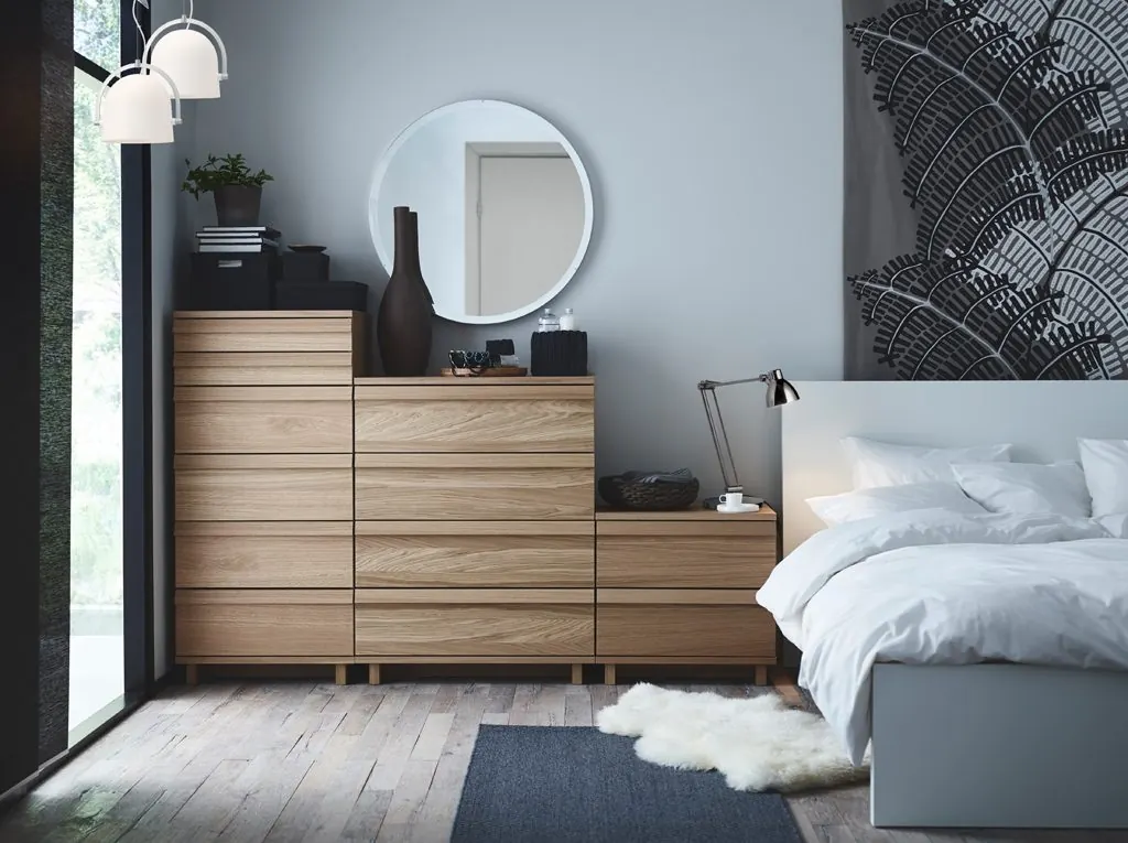 Minimal bedroom with oak drawers and a round mirror